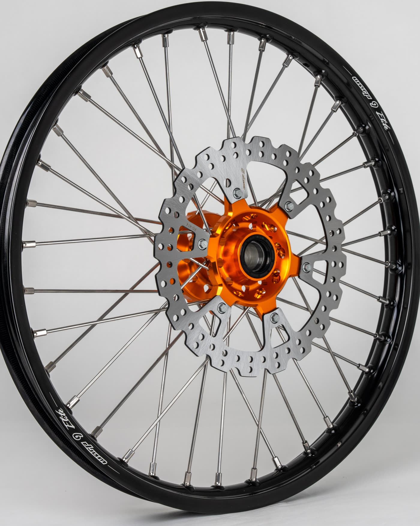 A Warp 9 front wheel, laced to an orange hub with a brake rotor fitted